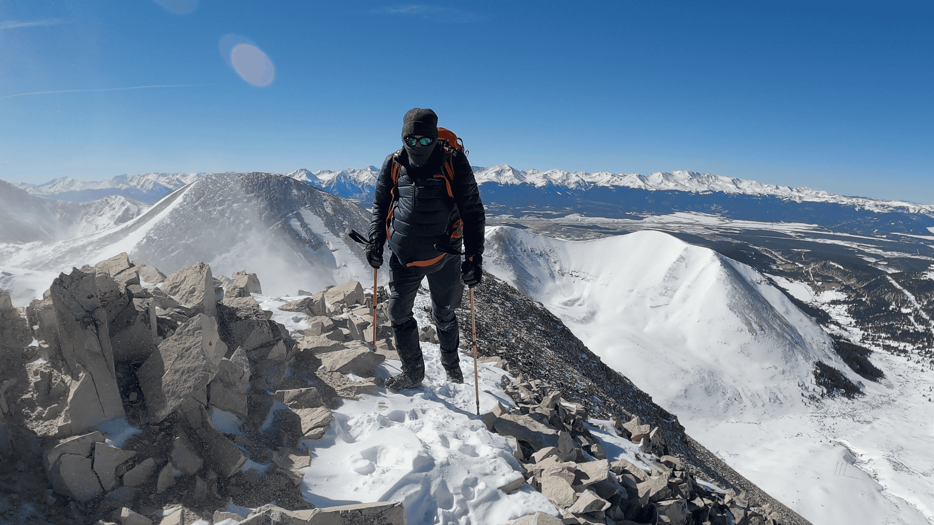 Matt walking along a rocky, snow-covered ridge above treeline
